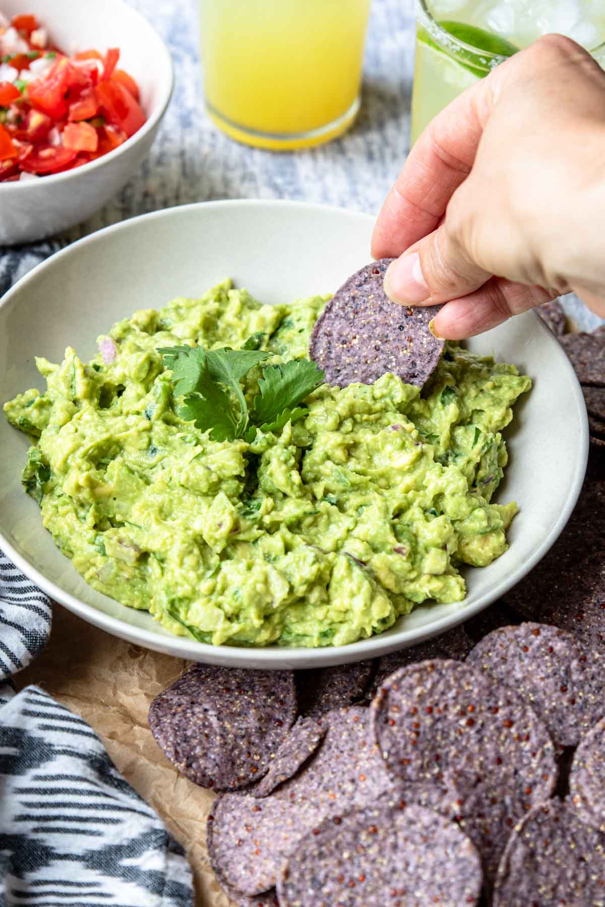 guacamole in a bowl being scooped with a blue corn tortilla chip