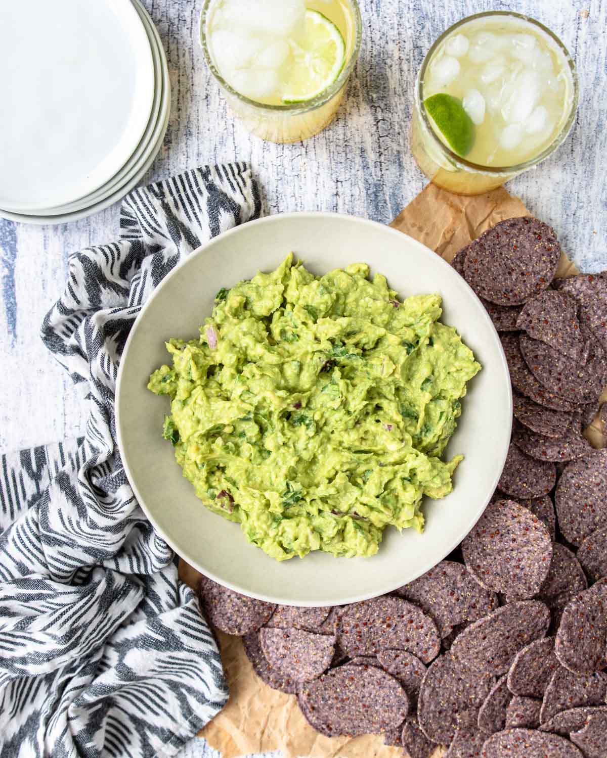 a table with margaritas, tortilla chips and guacamole