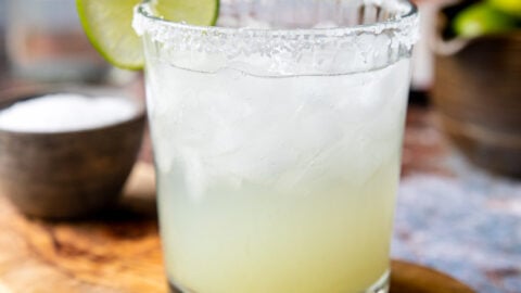 a salt rimmed glass with a classic margarita garnished with a lime