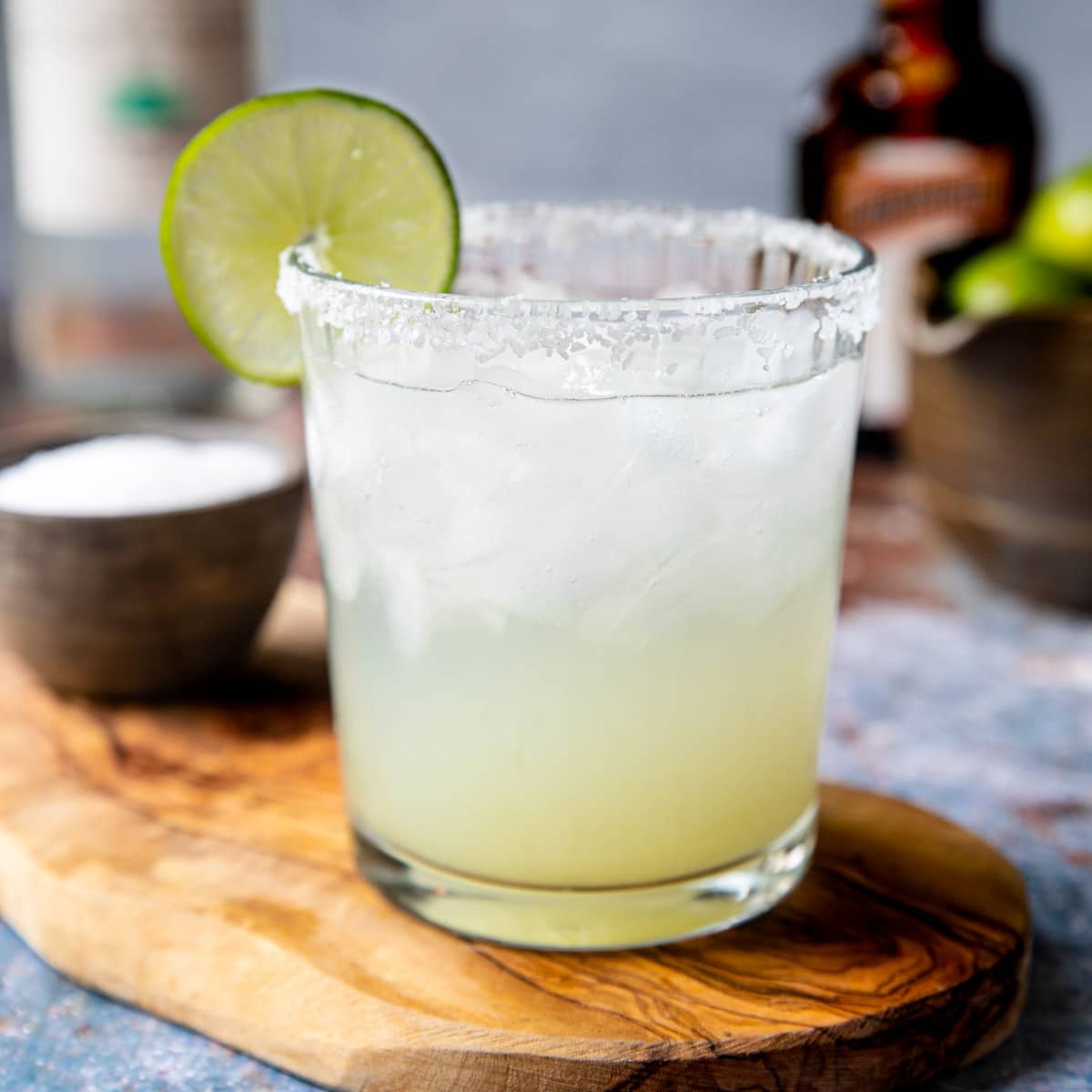 a salt rimmed glass with a classic margarita garnished with a lime