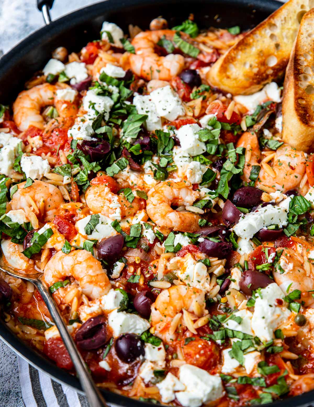close up of Mediterranean shrimp in a skillet topped with feta cheese