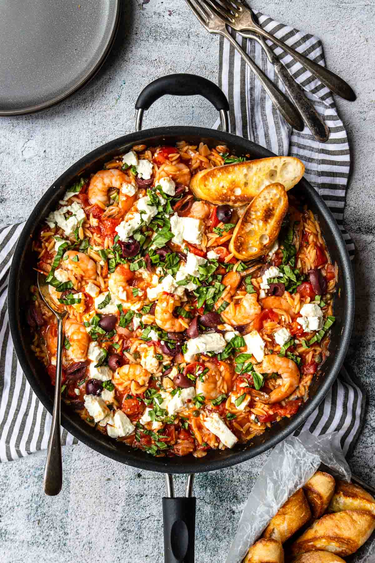 shrimp, tomatoes, olives, orzo and feta in a skillet