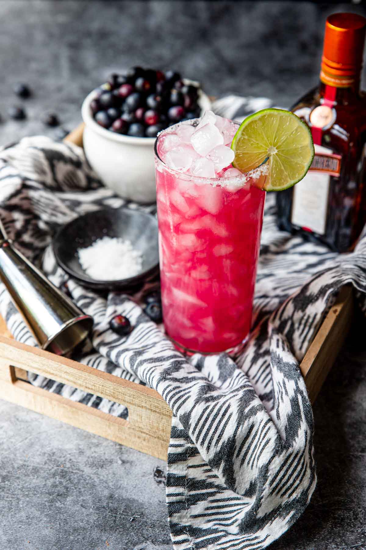 Blueberry margarita on a tray with fresh blueberries and cointreau