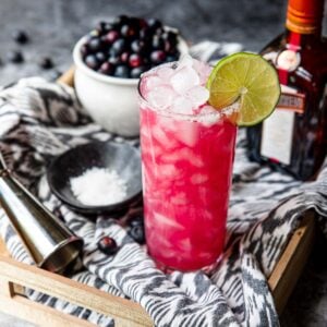 blueberry margarita cocktail in a glass with a lime wheel and fresh blueberries