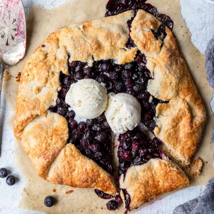 rustic blueberry pie (blueberry galette) on parchment paper with two scoops of ice cream
