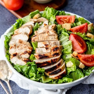 Grilled Buttermilk Marinated Chicken on top of a salad with tomatoes and croutons