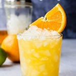 orange margarita in a glass with an orange wedge on top