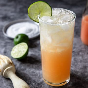 Paloma in a tall glass with lime wheel and salt on the rim