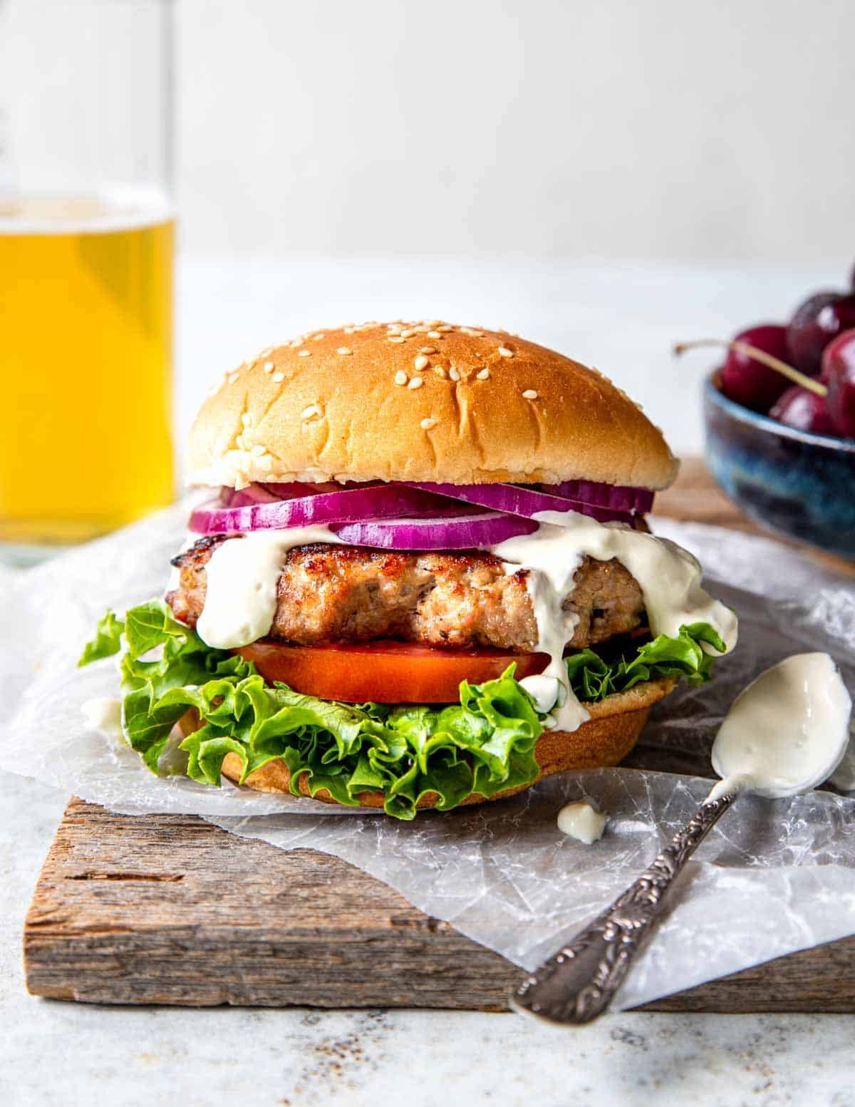 Grilled Pork burger on a bun with garlic cream sauce, tomato and lettuce