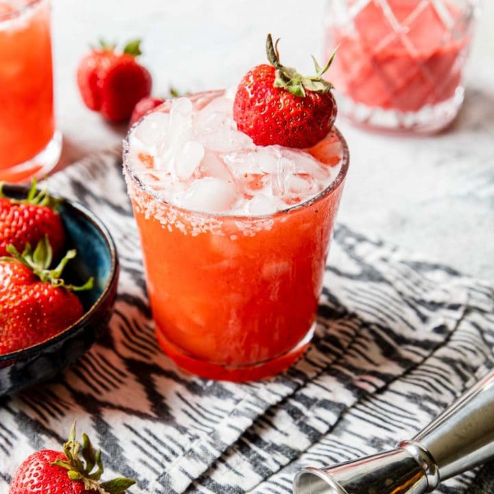 a glass of roasted strawberry margarita garnished with salt and berries