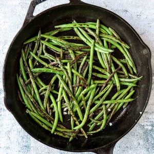 sauteed green beans in a pan with garlic and kosher salt