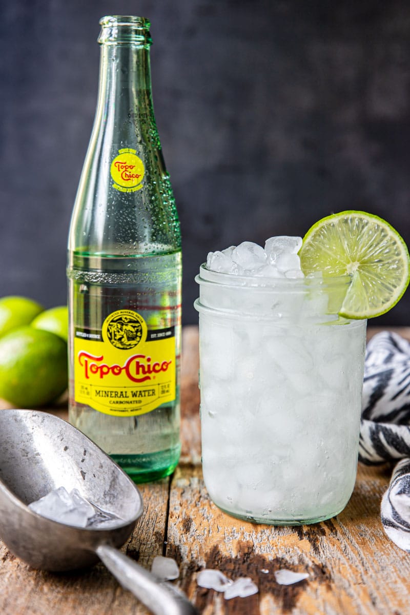 ranch water cocktail in a mason jar with a bottle of topo chico to the side