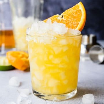 an orange margarita in a glass with an orange wedge
