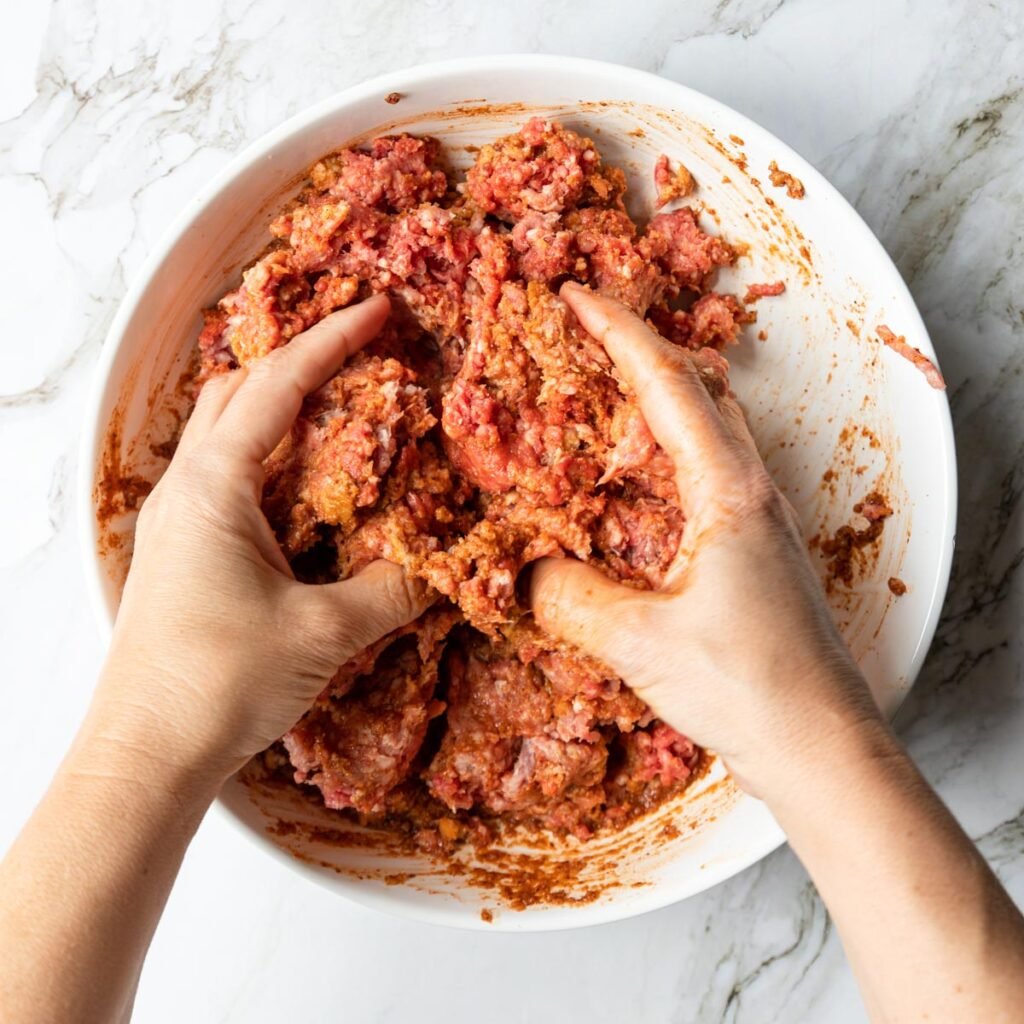 clean hands mixing meatball mixture in a bowl