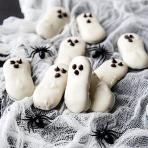 a couple ghost cookies on a spider web with spiders