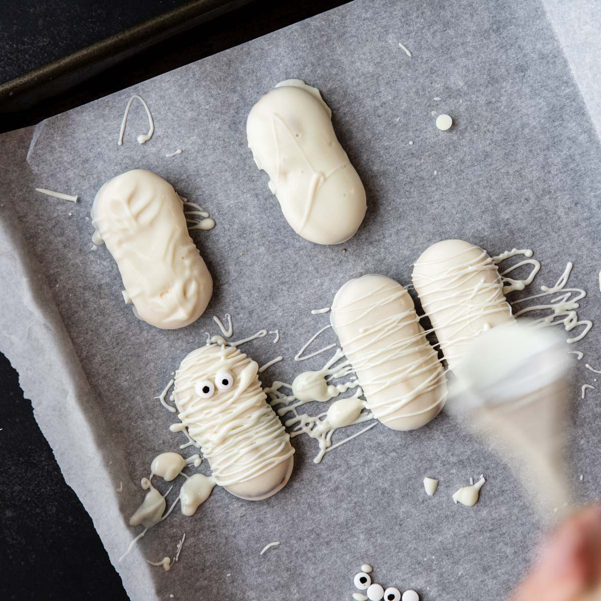 drizzling white chocolate on cookies to make them look like mummies