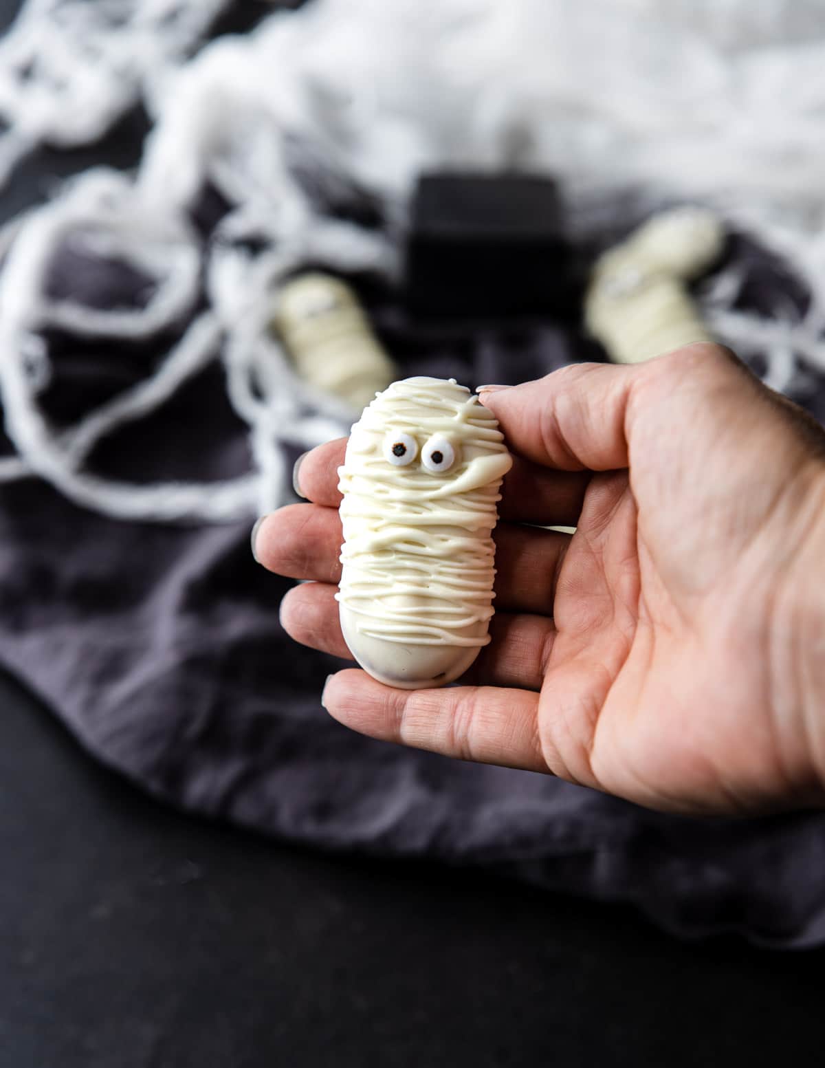 A hand holding a mummy cookie