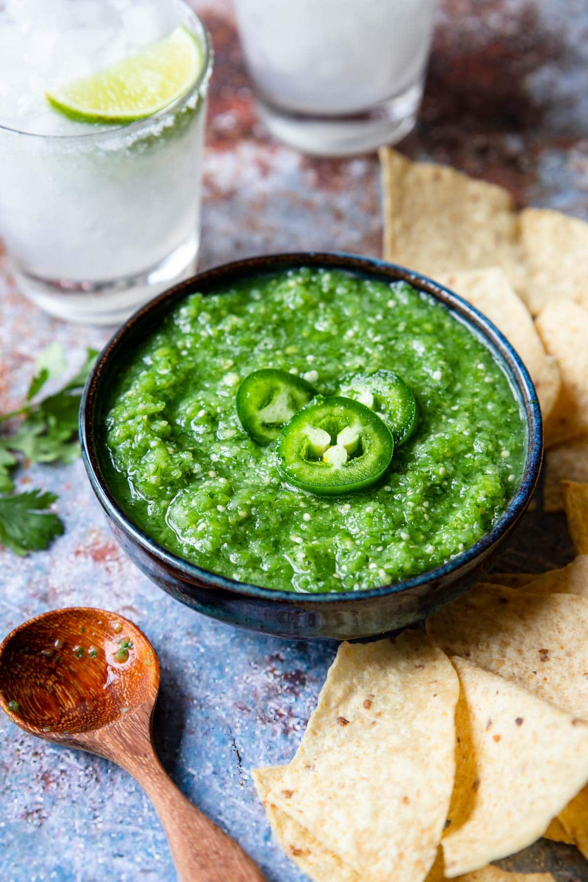 Tomatillo Salsa in a bowl topped with jalapeno and chips on the side