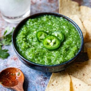 tomatillo salsa in a bowl with tortilla chips to the side