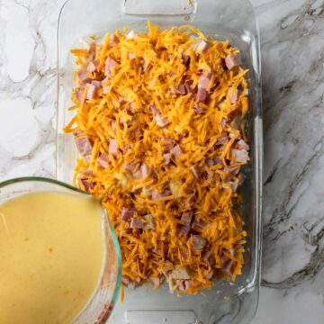 Pouring egg mixture over breakfast casserole