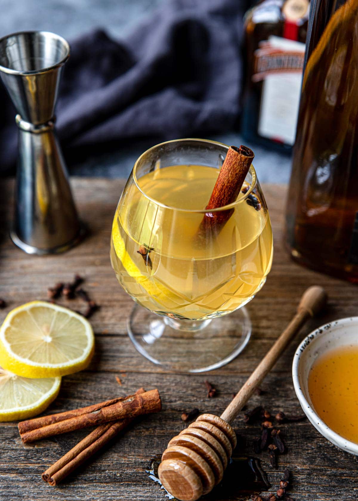 Tequila hot toddy in a glass with a cinnamon stick, lemon wheel and clove