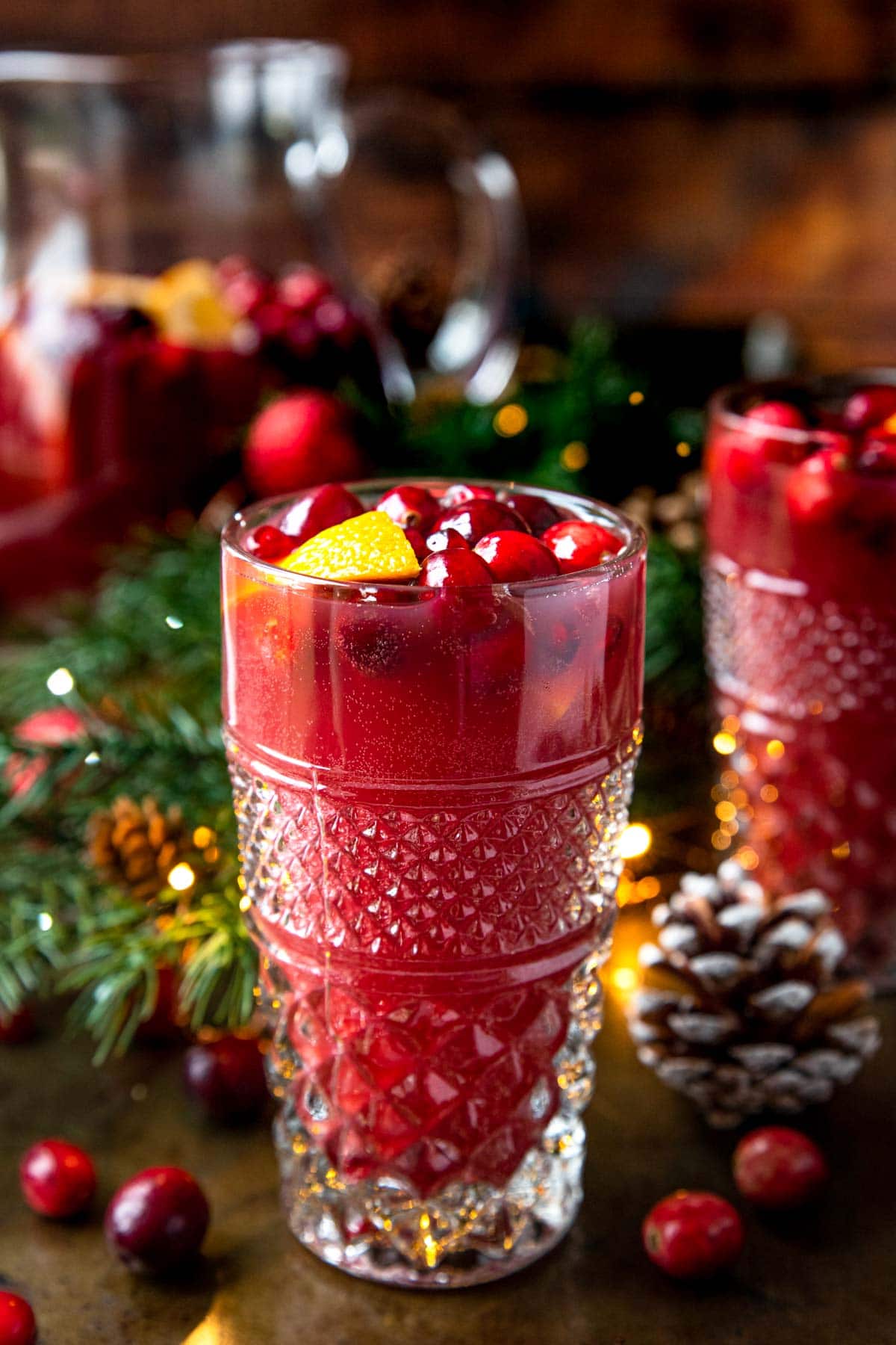 A glass of Christmas Punch garnished with cranberries and oranges