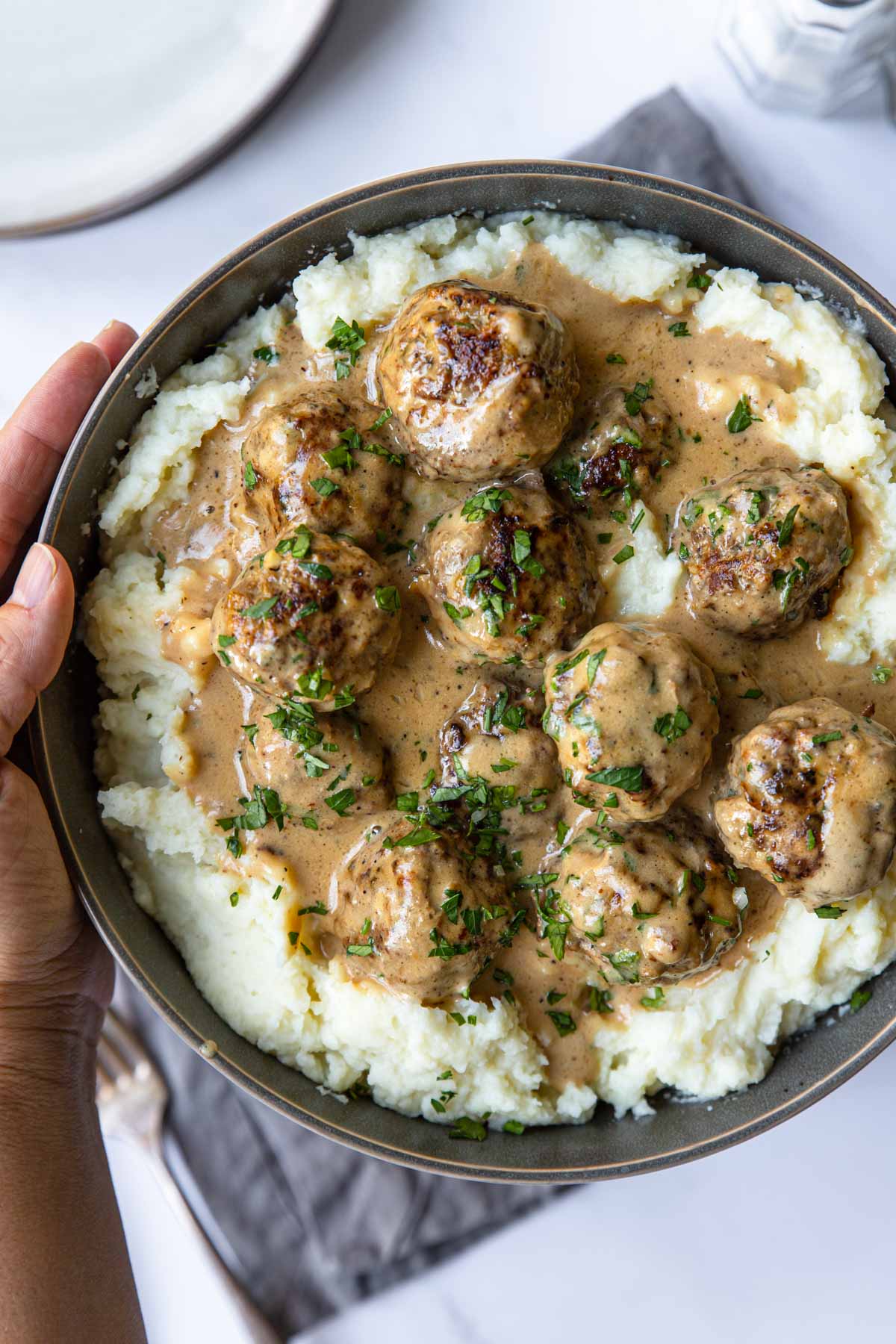 Swedish meatballs and sauce over mashed potatoes in a bowl