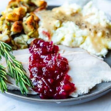 A plate of turkey, mashed potatoes and stuffing with cranberry sauce poured over the turkey