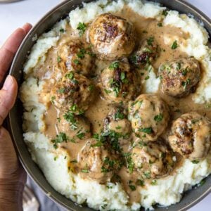 a large bowl filled with mashed potatoes topped with Swedish Meatballs