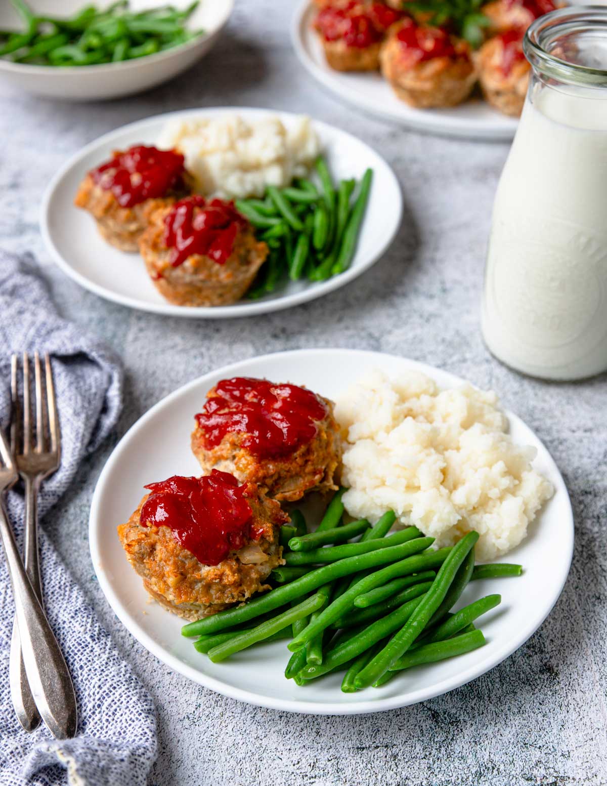 Turkey meatloaf cups on a plate with green beans and mashed potatoes