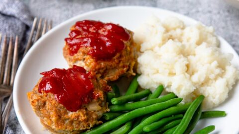 a plate with two turkey meatloaf muffins, green beans and mashed potatoes