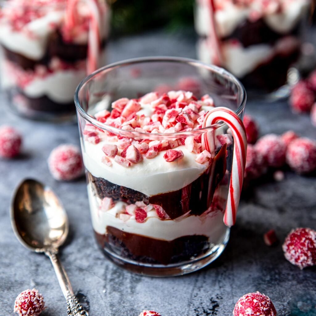 Layered chocolate and peppermint trifle with a candy cane on the side 