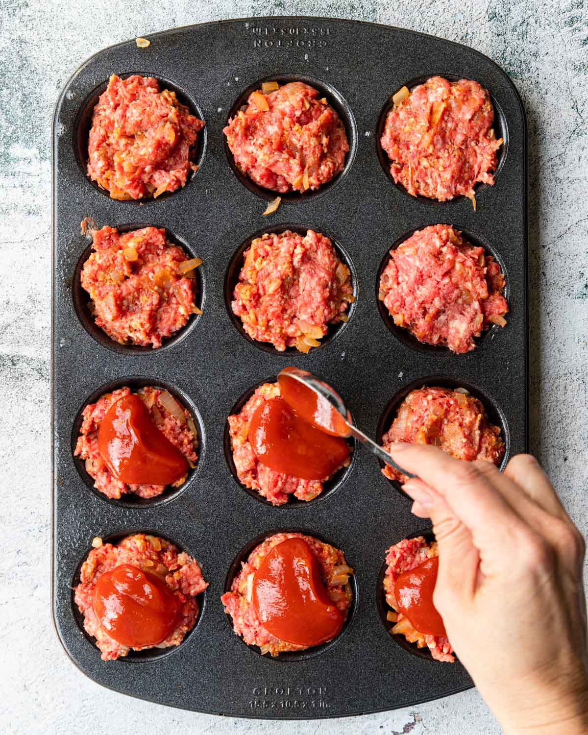 topping meatloaf muffin cups with ketchup