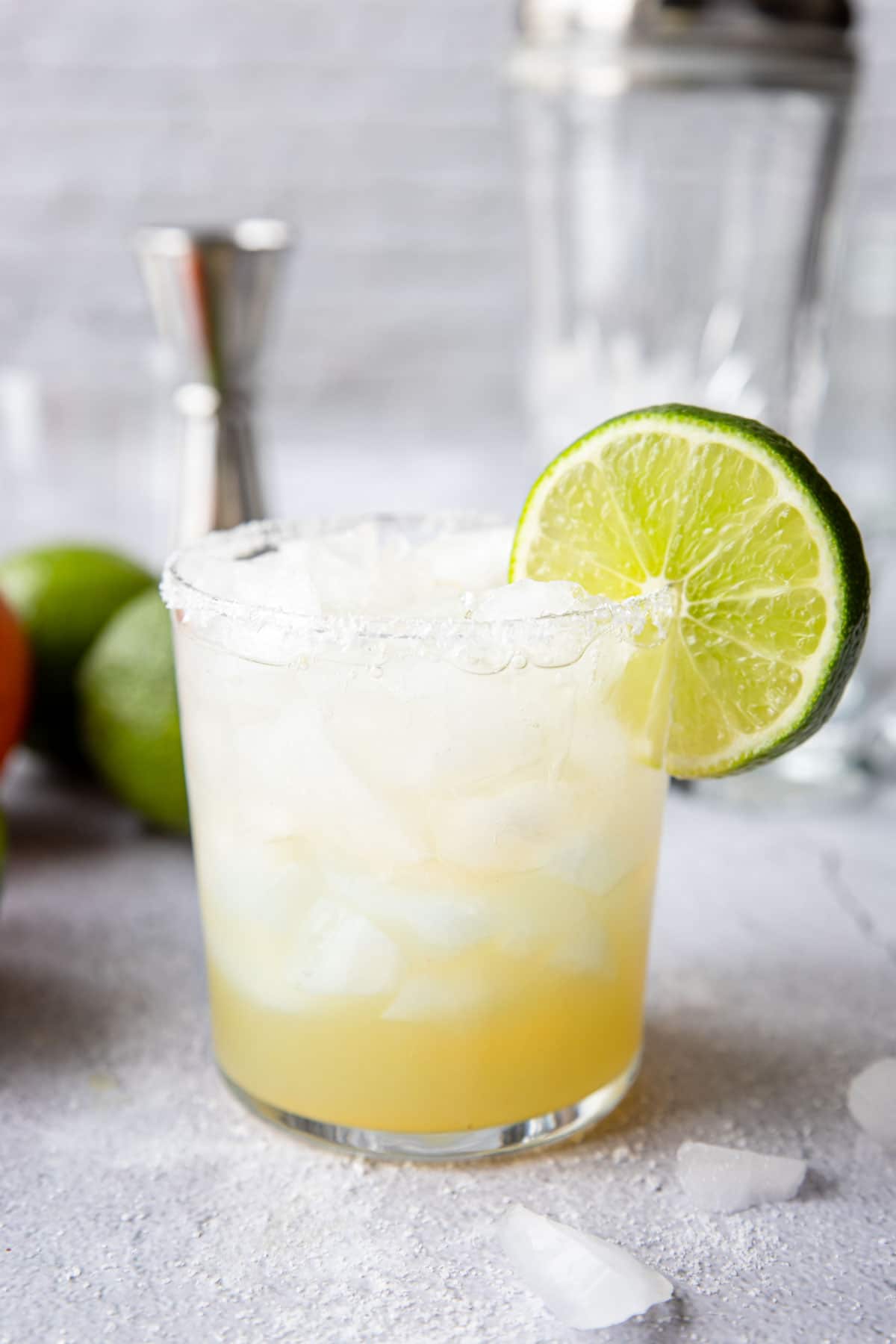 a clear glass with a mock margarita with a salt rim and lime wheel