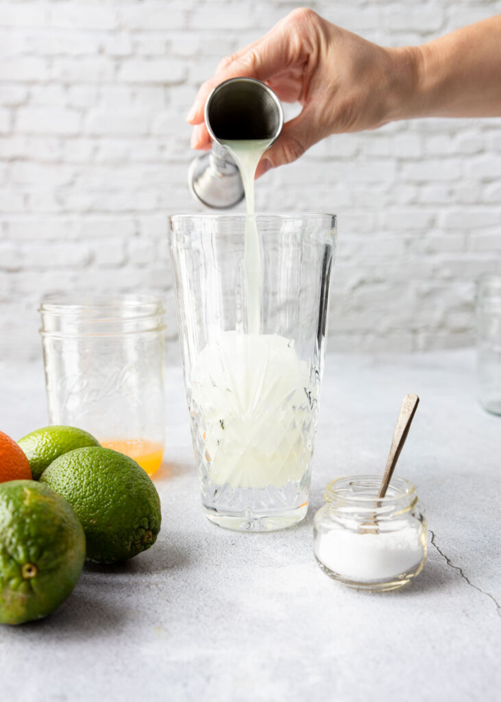 fresh lime juice being poured in a shaker