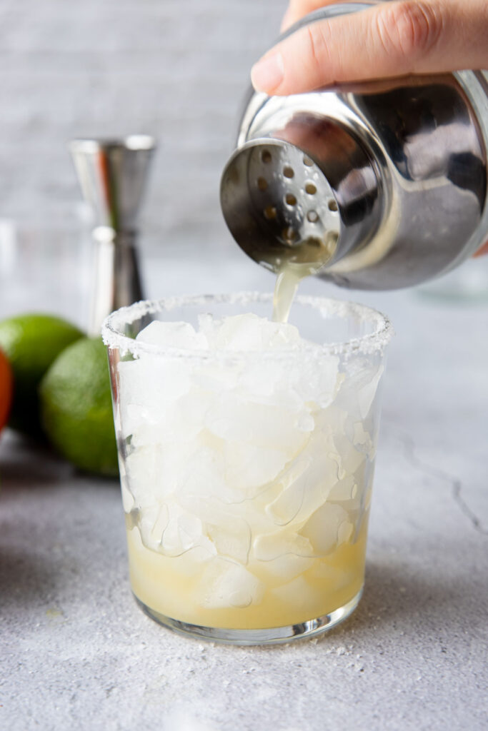 straining a non alcoholic margarita into a glass