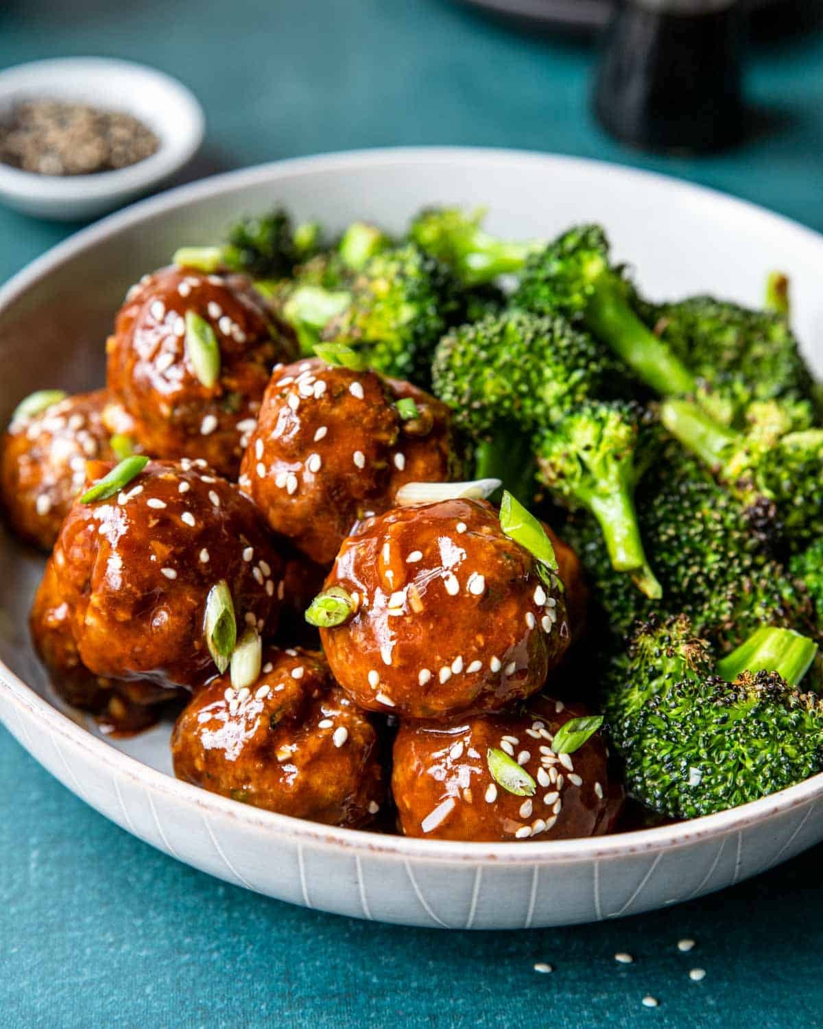 Hoisin Glazed meatballs in a bowl with roasted broccoli