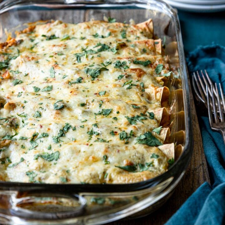 a pan of baked Chicken Enchilada Suiza garnished with cilantro