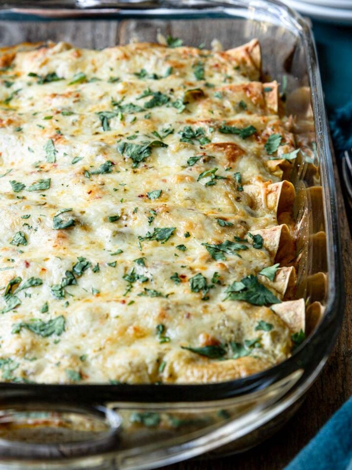 a pan of baked Chicken Enchilada Suiza garnished with cilantro