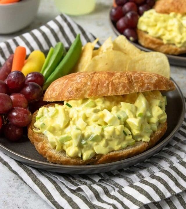 egg salad sandwich on a plate with chips and veggies
