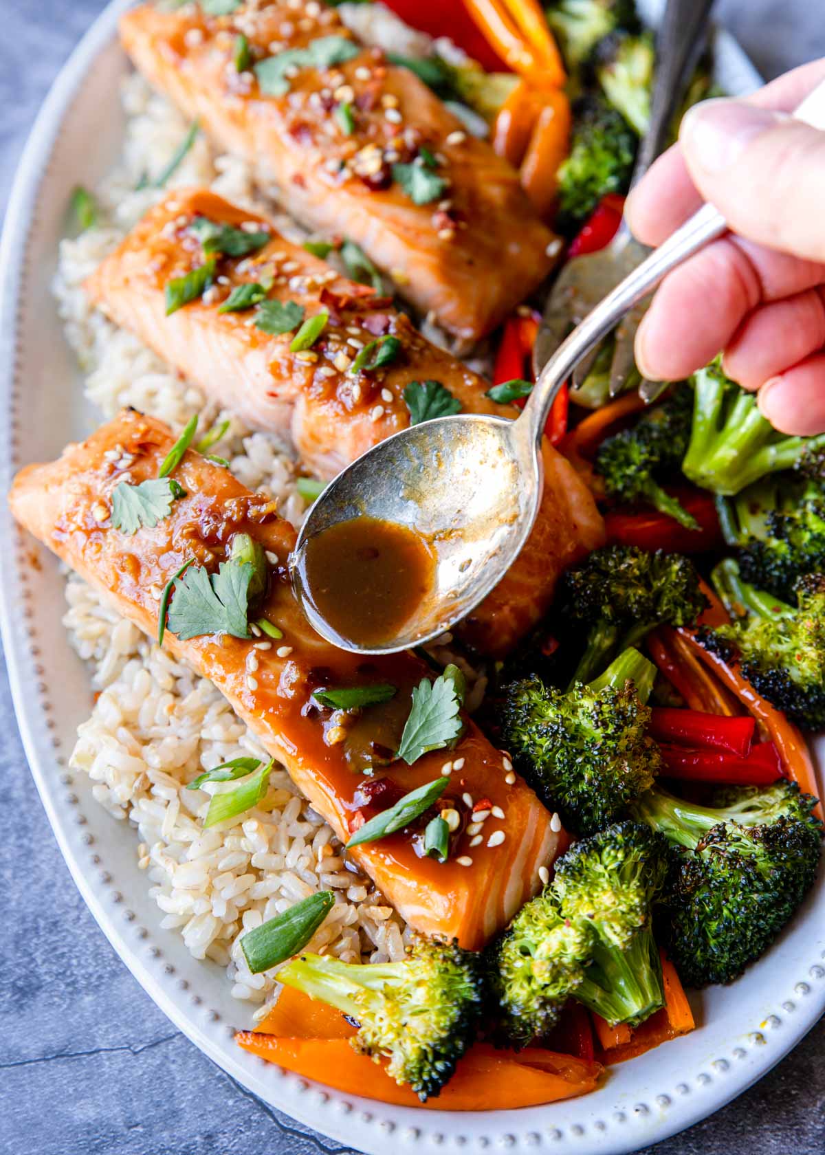 Asian Marinated Salmon on a plate with sauce being spooned over