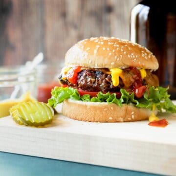 juicy burger on a bun with mustard, ketchup, lettuce and tomato