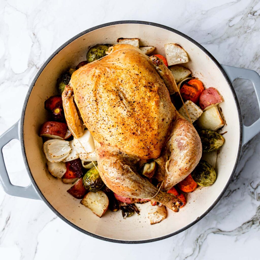 a dutch oven with a whole roasted chicken