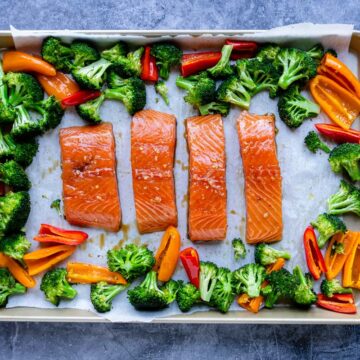 showing how to place the veggies and marinated salmon on the baking sheet