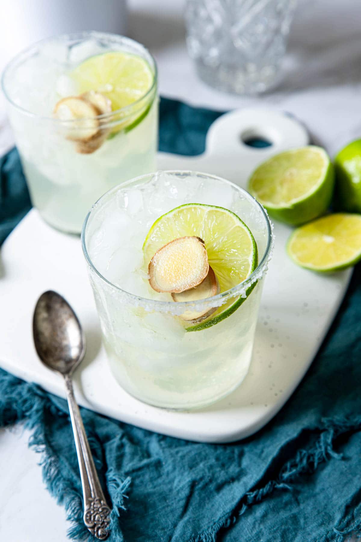 overhead shot of two ginger margaritas garnished with a lime wheel and ginger coins