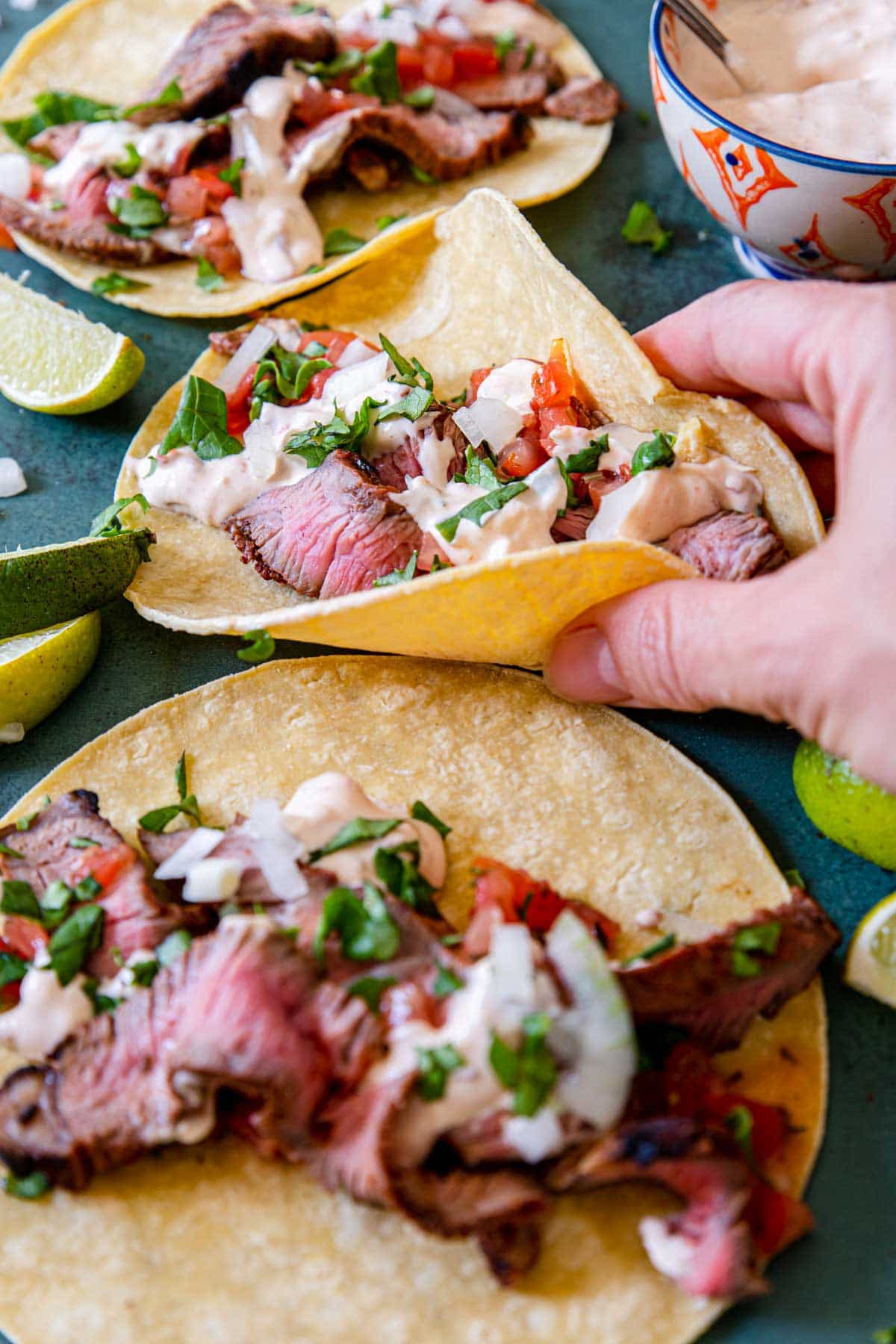 a hand picking up a grilled steak taco