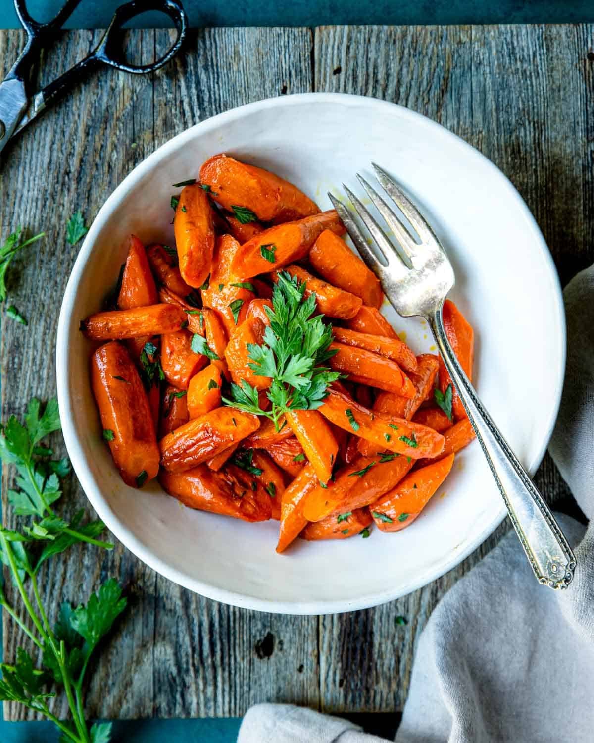 Roasted carrots in a white bowl with parsley garnish