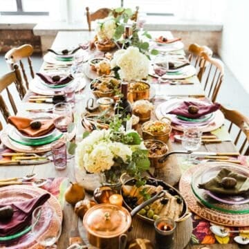 Large table set with plates, napkins, food and flowers