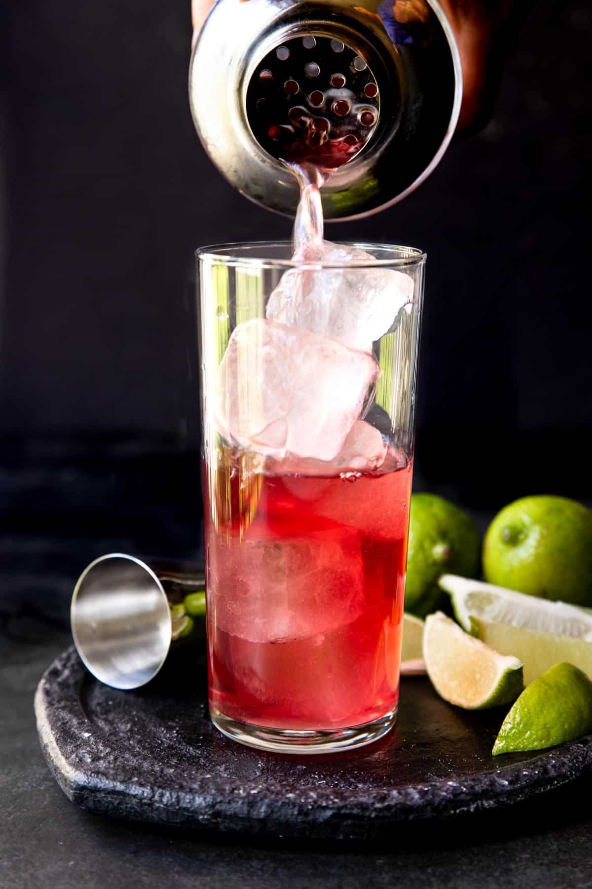 cocktail being poured from a shaker over ice