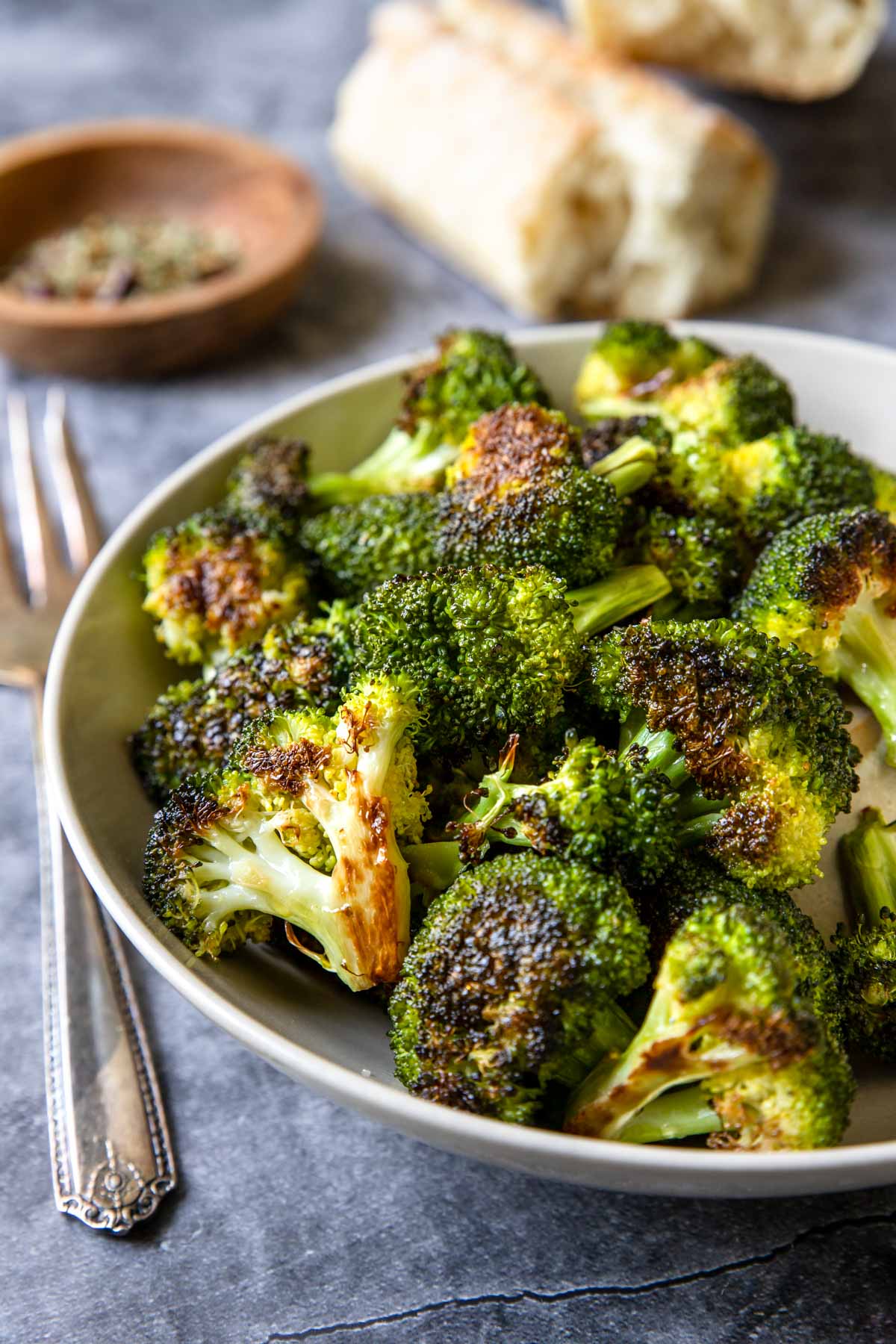 a bowl of roasted broccoli on a table